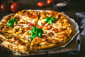 Whole tomato quiche with basil on wooden background