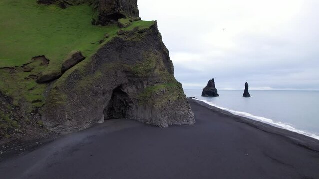 DRONE AERIAL FOOTAGE: Reynisfjara Black sand beach, Halsanefshellir cave, basalt columns and sea stacks at Vik i Myrdal in Iceland.
