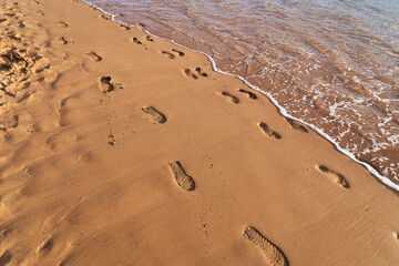 Footprints of different people on the ocean. Shoes or barefoot. The agony of choosing shoes