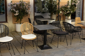 Empty restaurant summer terrace with tables and chairs. Reastaurant tables waiting for customers at an outdoor terrace, hipster style
