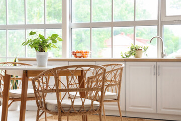 Interior of light kitchen with white counters, dining table and big window