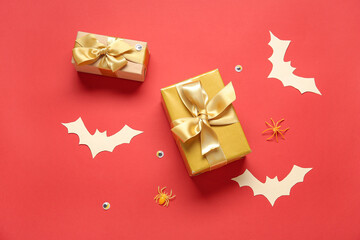 Composition with beautiful gift boxes and Halloween decor on red background