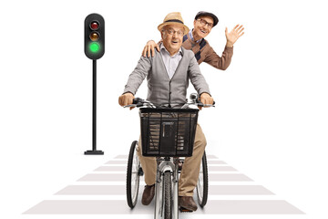 Two elderly men riding on a tricycle towards camera at pedestrian crosswalk