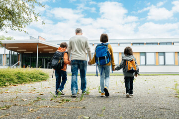 Back to school. A father walks his children to school. Beginning of the school year. Parental care...