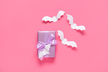 Composition with beautiful gift box and bats made of paper for Halloween on pink background