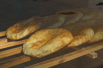 Freshly baked pita bread lies on a wooden rack in a bakery.