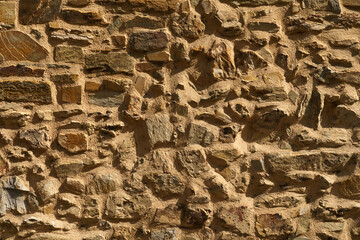 The texture of the old medieval wall of the house, lined with brown stone