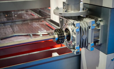 Close up of drive sprockets and industrial drive roller chains in production machine line without...
