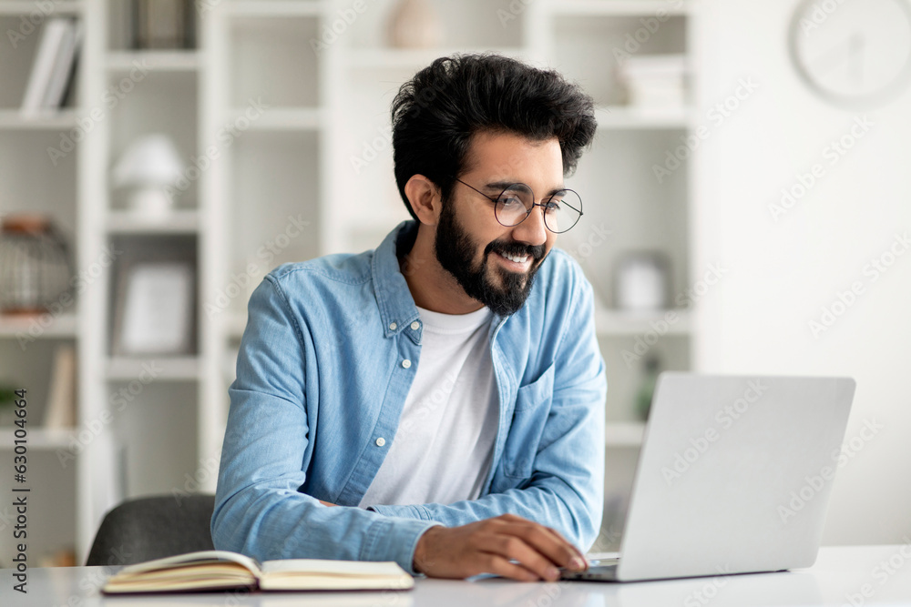 Aufkleber networking concept. handsome young indian guy browsing internet on laptop computer