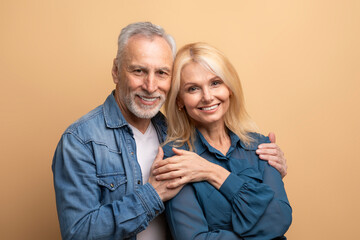 Portrait of loving happy senior couple spouses posing on beige