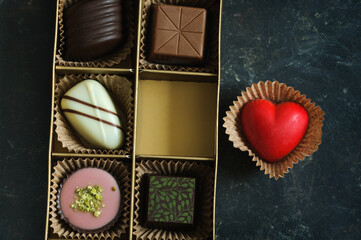 A set of beautiful sweets in a close-up box on a dark marble background. Top view, natural light. The concept of holidays, Valentine's Day