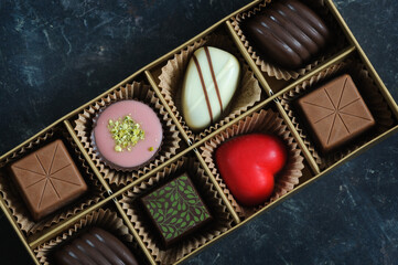 A set of beautiful sweets in a close-up box on a dark marble background. Top view, natural light. Concept for Valentine's Day and other holidays
