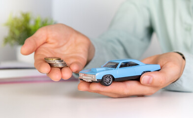 Toy car in hand, keys and money on table. Car loan, money, car insurance concept