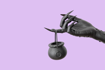 Black hand of witch and cauldron on purple background. Halloween celebration - obrazy, fototapety, plakaty