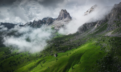 A beautiful view of a mountain green range or alpine meadows with a beautiful landfall, drone view. Passo Giau or Giau Pass aerial view with green mountain views and fog
