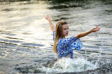 A young girl splashing in the river water on a hot summer evening