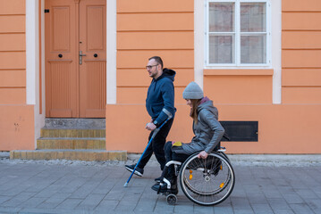 Friends with a disability. Woman in a wheelchair and man with a walking stick