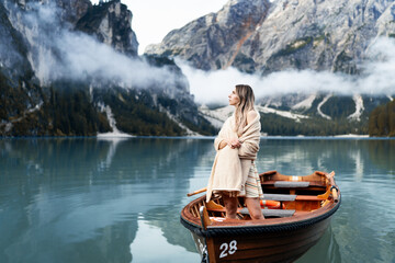 Beautiful girl standing on a boat and holding oars on the famous blue lake. Stunning romantic place with typical wooden boats on the alpine lake,(Lago di Braies) Braies lake,Dolomites,South Tyrol