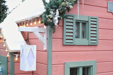 Christmas porch decoration idea. House entrance and window sill decorated for holidays. New year winter front yard festive snow tree garlands on facade