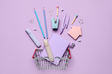 Composition with shopping basket and different stationery on lilac background