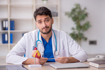 Young male doctor cardiologist sitting at the hospital