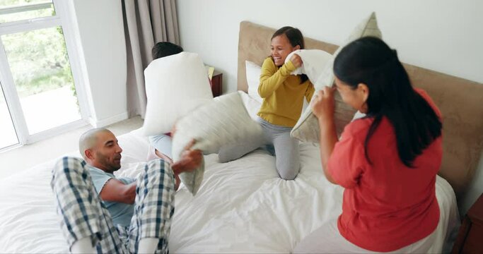 Happy family, play or pillow fight on bed in home for bonding on holiday or weekend morning together. Father, mother or playful children laughing to enjoy fun games with pillows in bedroom to relax