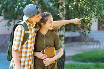 school students, a teenage boy and a girl are walking down the street, having fun, a boy pointing...