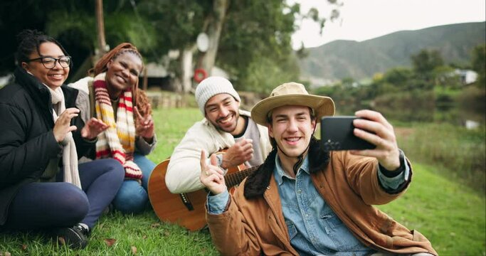 Camping, selfie and friends at a forest lake bond, happy and and enjoying guitar music in nature. Smartphone, profile picture and group of people relax in the woods, fun and enjoying freedom at river
