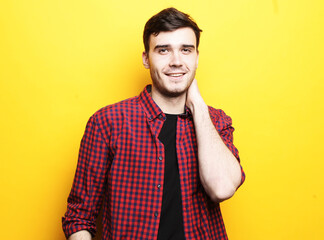 Smiling handsome male model in casual shirt on a yellow background.