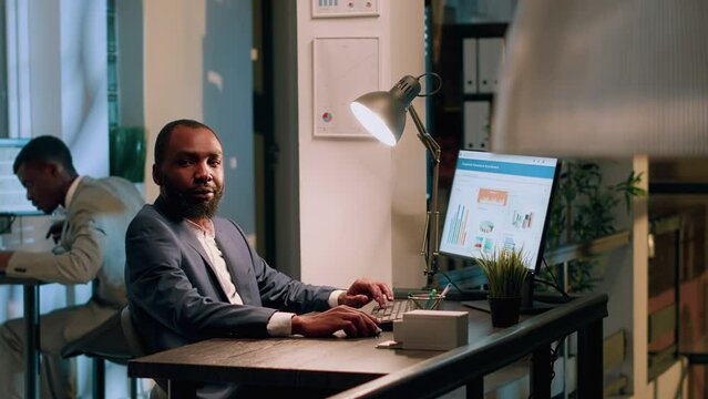 Happy bookkeeper keeping online records, putting together and organizing data, preparing to submit reports in office during nightshift. Smiling employee checking documents for accuracy