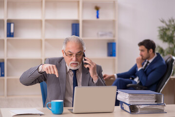 Old male boss and young male employee in the office