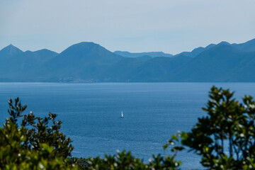 Fototapeta na wymiar Beautiful view of a distant sailboat sailing peacefully on the blue Adriatic Sea
