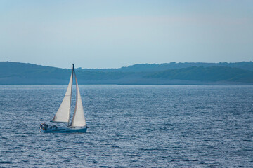 Sailing boat moving gracefully on wavy blue sea between scenic Croatian Islands