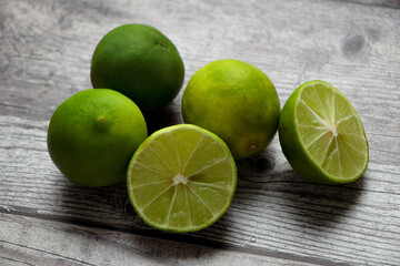 limones en una mesa gris rústica, uno de los limones se corta por la mitad. - obrazy, fototapety, plakaty