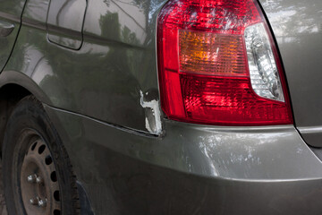 Damaged rear fender and headlight of a car. car accident. Dent in metal, paint peeled off....