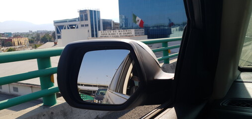 Side mirror, second floor, mexican flag, buildings, cars, traffic, sky, mountains at cdmx, mexico