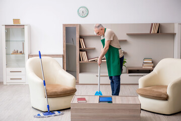 Old male contractor cleaning the house