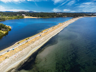 Aerial Esquimalt Lagoon sand spit overlooking Royal Roads University with a long straight road in Victoria British Columbia Canada.
