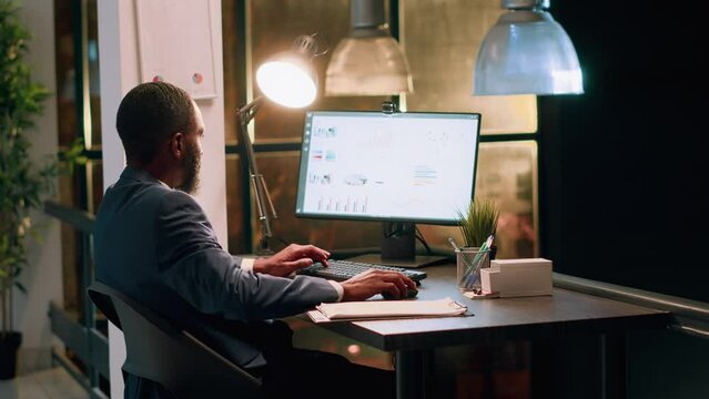 Bookkeeper in office making sure documents are compliant with quality assurance expectations and standards during nightshift. Employee checking paperwork details on computer screen
