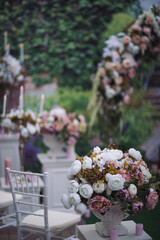 Wedding Florals at a summer wedding aisle ceremony. Luxury floral arrangement. Beautiful decorated table set for wedding party. Beautiful bouquet in a vase on a background of a wedding arch.