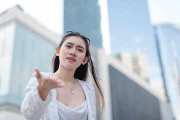 An irate young woman argues and talks down to someone. Outdoor city scene, copyspace on the right.
