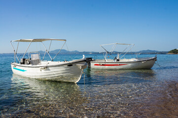 Two empty modern boats floating in beautiful blue sea on a sunny day. Mediterranean seacoast lonely beach.