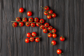 Fresh cherry tomato branch on wooden background top view.