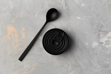 Tin can and spoon on gray background top view