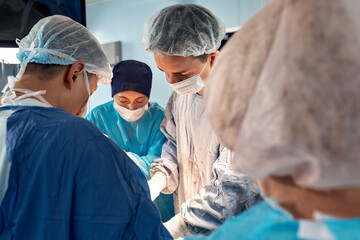 Portrait of surgeons leaned over patient during complex surgical operation in a sterile operating room. Doctors are focused and extremely attentive. Precision medicine, saving patient's life.