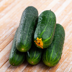 Many ripe juicy cucumbers on wooden surface closeup