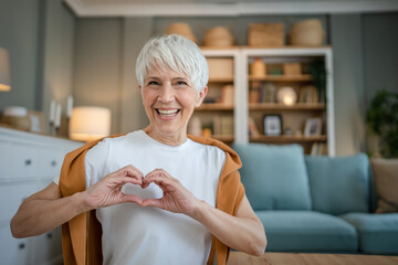 healthy senior caucasian woman showing hart hand gesture health love