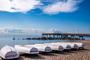 Lifeguard skiffs inverted on an empty beach at morning with puffy white clouds in the background. ...