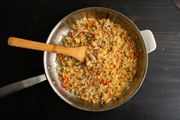 Thai Style Crab Fried Rice in a Large Skillet with a Bamboo Spatula: A frying pan filled with freshly made seafood fried rice viewed from above