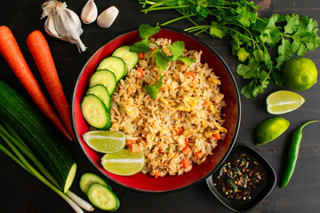 Thai Style Crab Fried Rice with Cucumber, Lime, and Cilantro: A bowl of seafood fried rice with sauce and surrounded by fresh vegetables